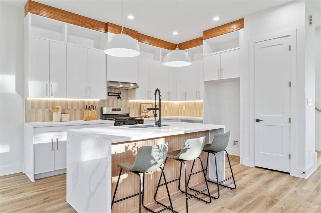 A beautifully designed chef’s kitchen boasting a large waterfall island with quartz countertops and bar seating.