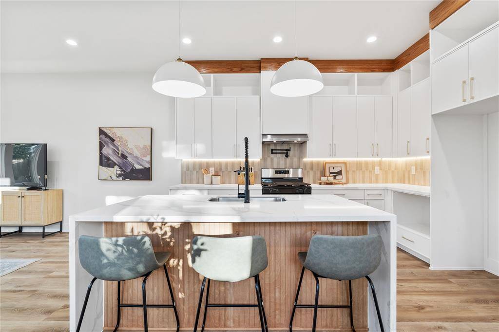 Pendant lighting over the island adds a touch of sophistication alongside a flute paneled island.