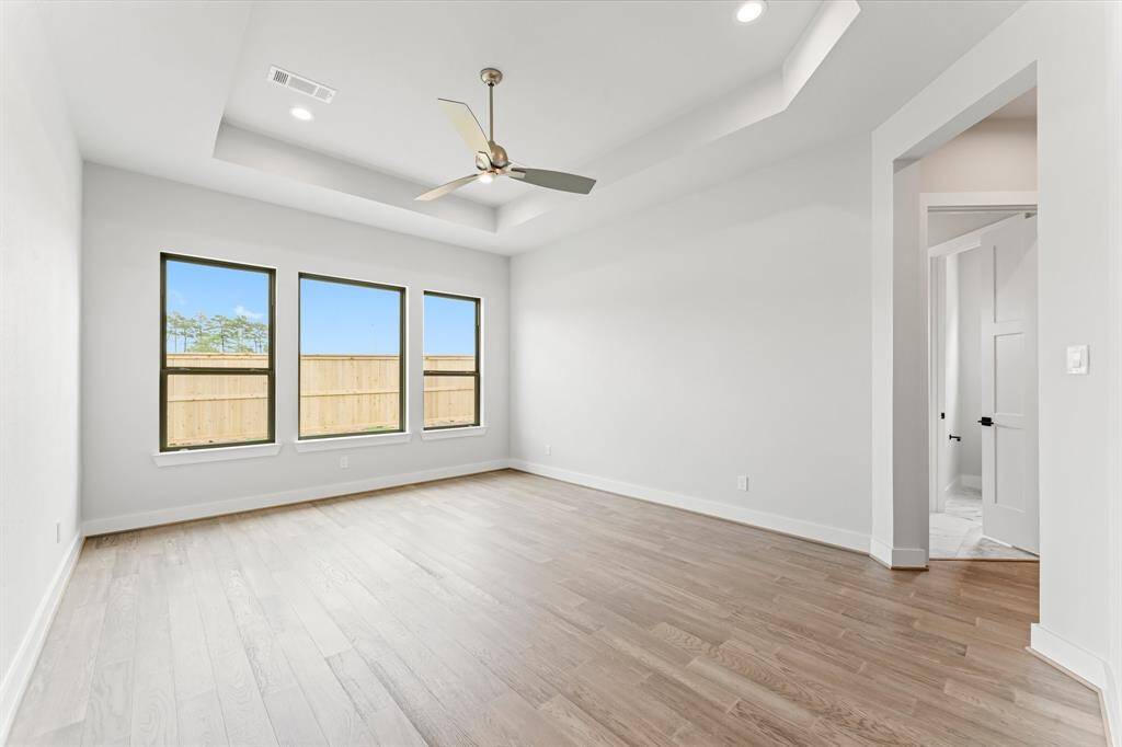 Primary Bedroom with Engineered Hardwood Flooring, Modern Fan, and 2 Walk-in Closets