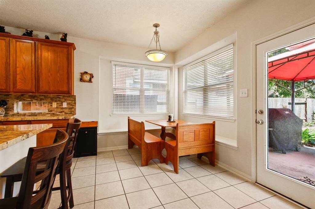 This bright kitchen features a cozy breakfast nook with, a tile floor, and large windows for plenty of natural light. The space opens to a patio through a glass door, offering easy access to outdoor dining and entertaining.