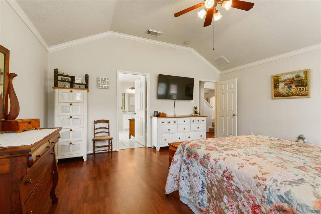 This bedroom features a cozy, inviting space with wood laminate flooring and neutral walls. It includes a ceiling fan.