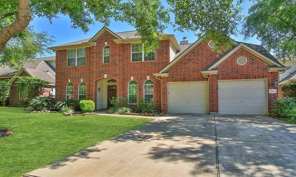 This charming two-story brick home features a well-maintained front yard with lush greenery and mature trees. It includes a double garage and a welcoming entrance with arched windows, offering a blend of classic and modern appeal.