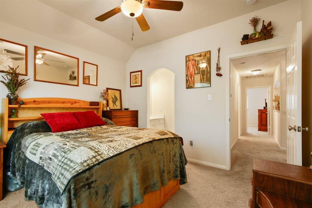 This cozy bedroom features a ceiling fan, neutral walls, and carpeted flooring.