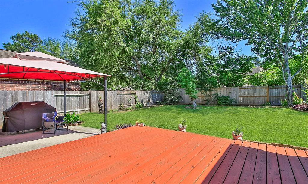 Spacious backyard with a wooden deck, shaded seating area, and well-maintained lawn. Perfect for outdoor entertaining and relaxation.