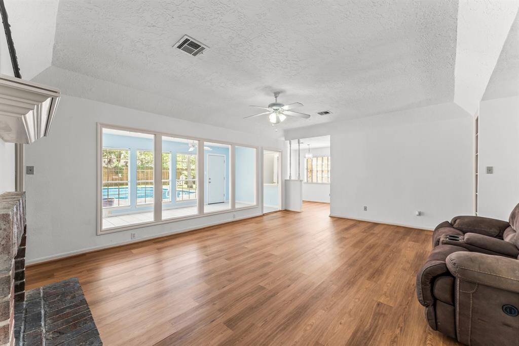 Spacious living room is connected to the sunroom, overlooking the glittering pool.