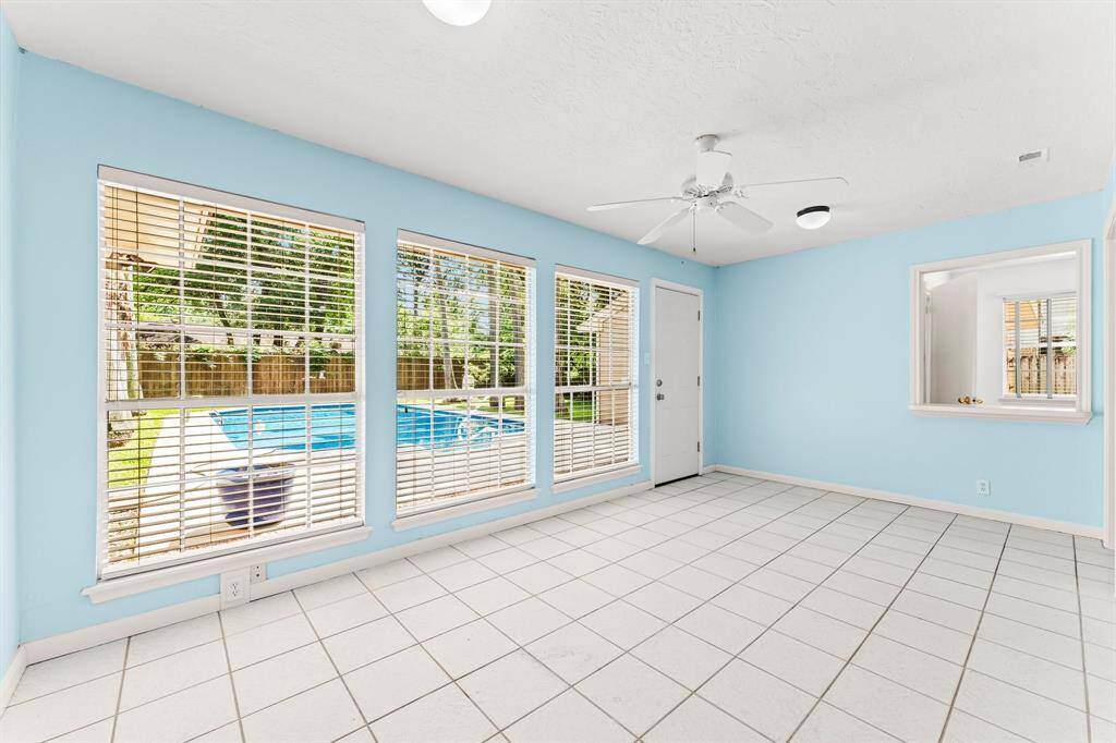 Beautiful sun room overlooks the sprawling backyard with a glittering pool and mature trees.
