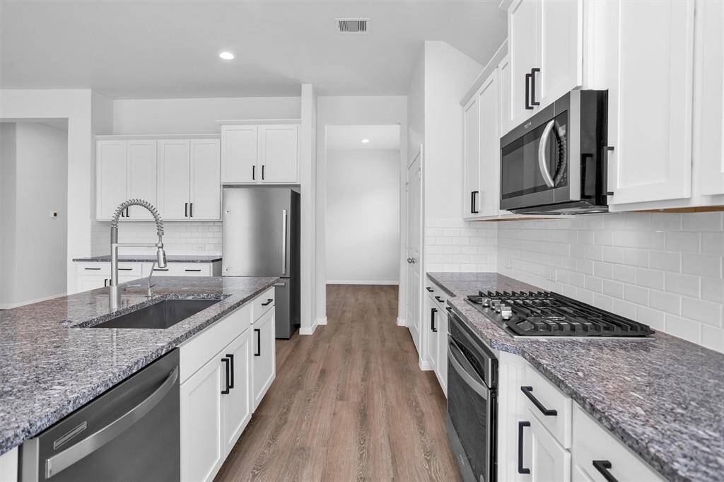 A classic white subway tile backsplash adds a timeless touch, and stainless steel appliances—including a gas range—complete the modern look. Recessed lighting and large windows fill the space with natural light, making it feel warm and welcoming for everything from morning coffee to holiday hosting.
