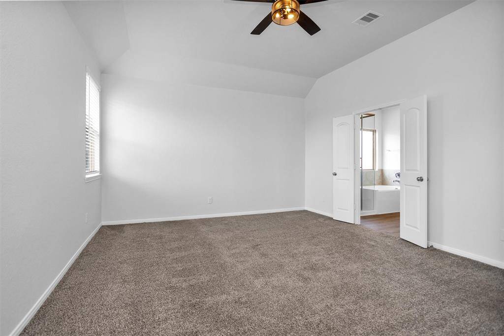 Retreat to the spacious primary suite tucked at the back of the home, with plush carpet, large windows, and plenty of room for a king-size bed and sitting area.