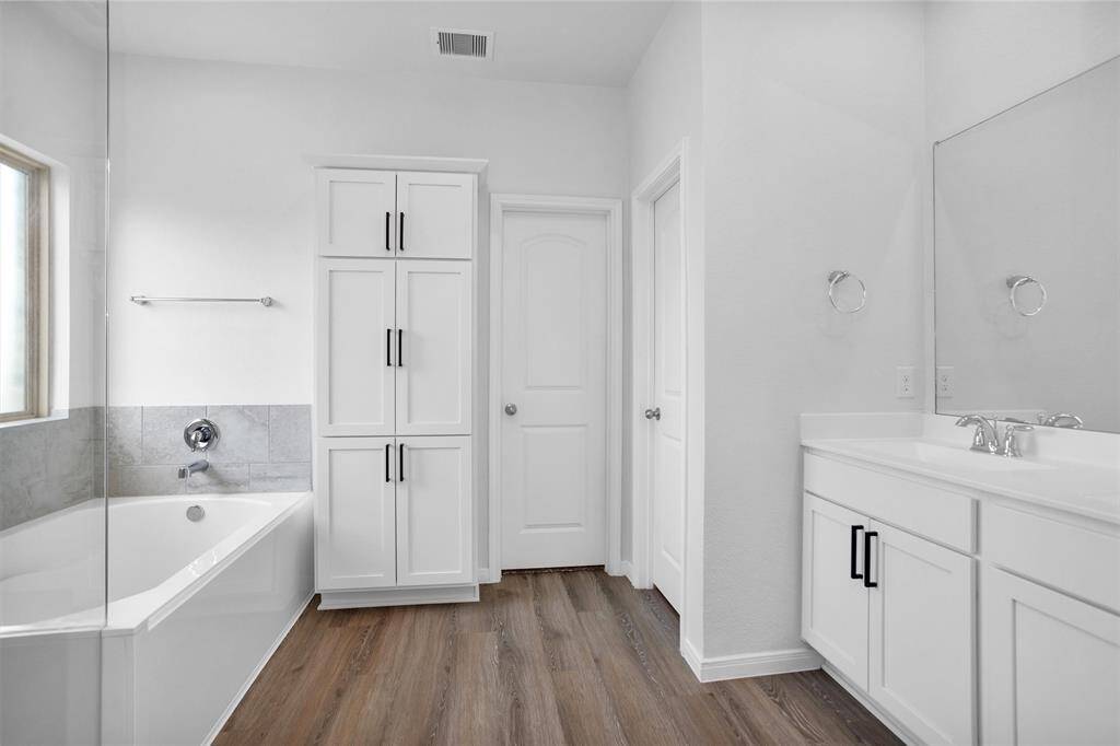 Spa-inspired primary bathroom with a sleek frameless glass shower, dual vanities with granite counters, and a walk-in closet large enough to keep everything organized.