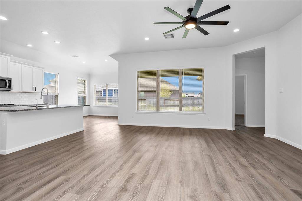 The open-concept living area offers generous space for relaxing or entertaining. Luxury vinyl plank floors, soft neutral colors, and backyard views create a cozy yet modern vibe.