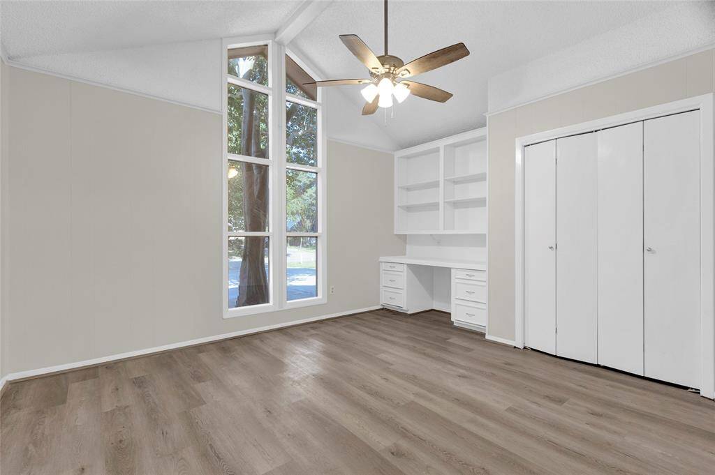 This flexible space serves beautifully as a 5th bedroom, home office, or creative studio. Floor-to-ceiling windows bring in an abundance of natural light, accentuating the vaulted ceilings and creating an open, airy atmosphere. Built-in shelves and a custom desk provide excellent functionality, while the full-size closet adds convenience and versatility for use as a guest room or additional bedroom.