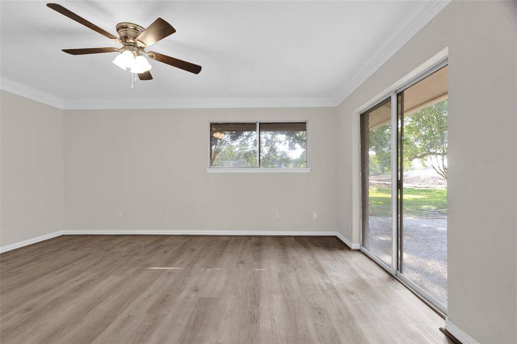 Unwind in this serene primary suite featuring luxury vinyl plank flooring, crown molding, and abundant natural light. Sliding glass doors offer peaceful views and direct access to the backyard—perfect for morning coffee or evening relaxation.