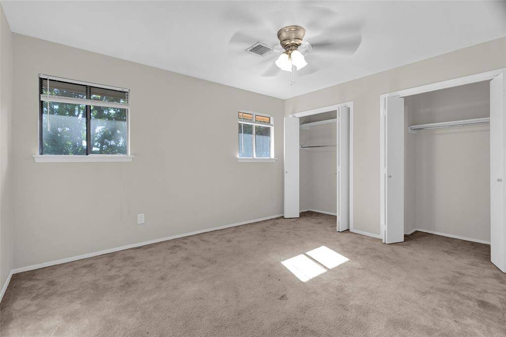 This cozy secondary bedroom features soft carpeting underfoot, a neutral palette, and plenty of natural light. With dual closets, there’s ample storage space to keep things tidy and organized.