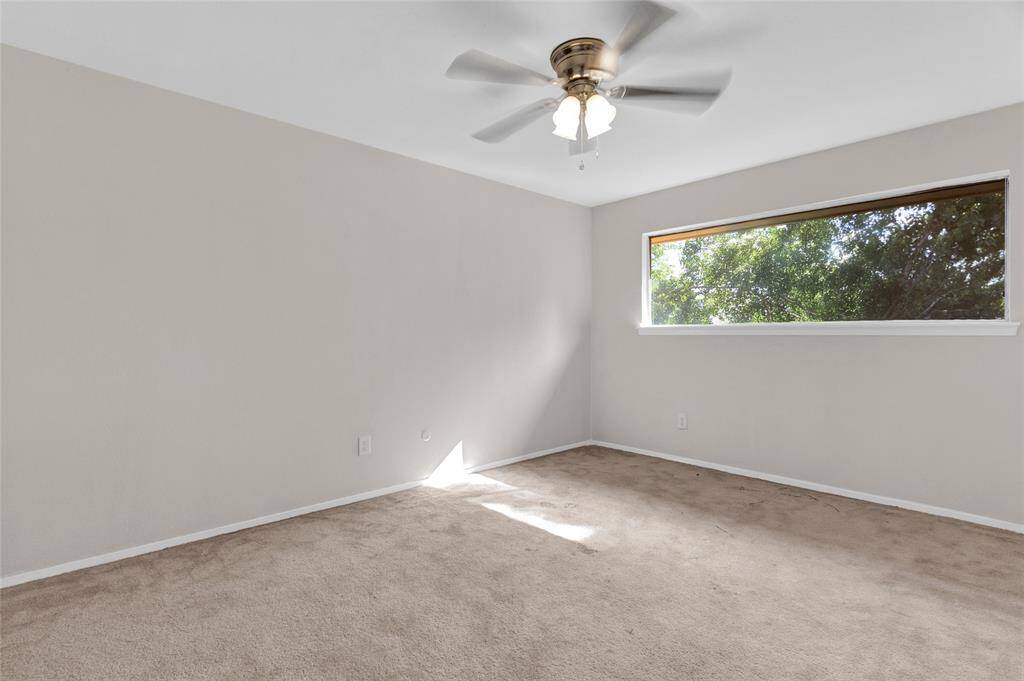 This peaceful third bedroom offers a quiet retreat with soft neutral tones and plush carpeting underfoot.