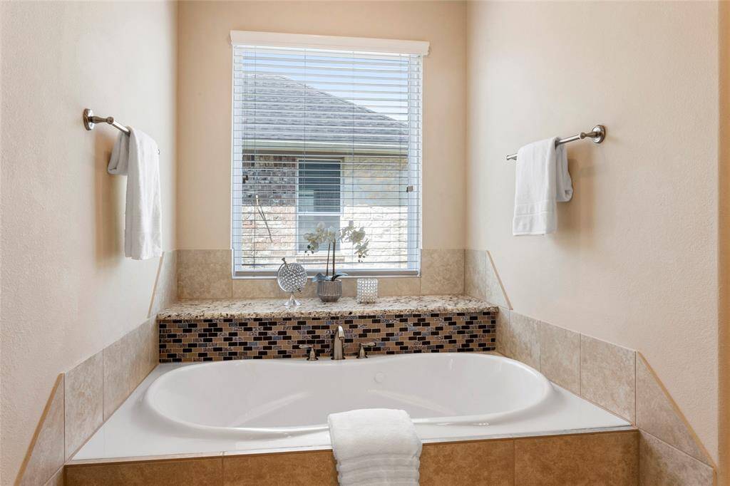 Built-in soaking tub with a mosaic tile accent.