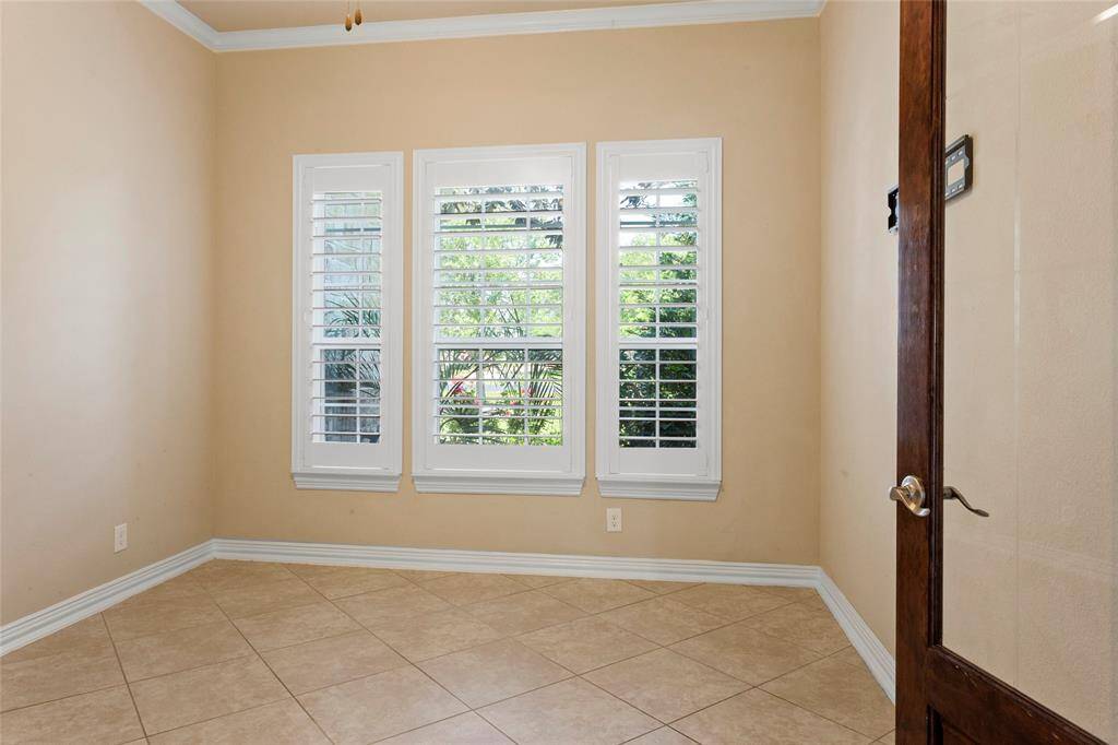 The Home Office offers glassed French doors and ample natural light from three large windows with plantation shutters, creating a bright and welcoming space.