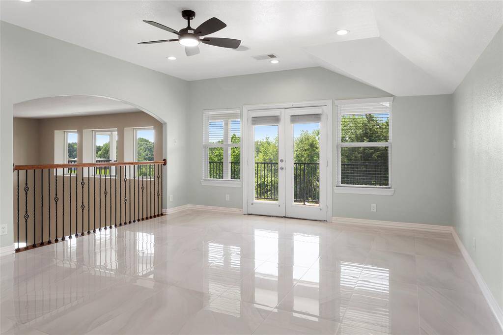 The spacious Game Room upstairs leads out to the balcony overlooking the backyard.  The open railing and arched entryway enhance the airy feel.