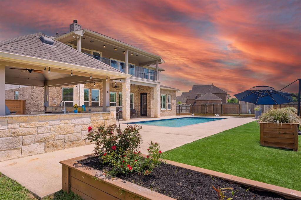 This stunning backyard features a beautiful pool, a covered patio with an outdoor kitchen, and well-maintained landscaping, a dog run, outdoor pool bathroom and artificial turf for easy care. Perfect for entertaining and enjoying evening sunsets.