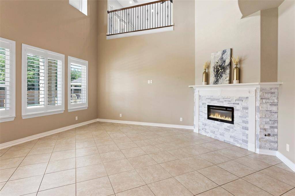 The neutral tones and plantation shutters offer a clean, elegant look, while the open loft area above adds a sense of openness and flow.