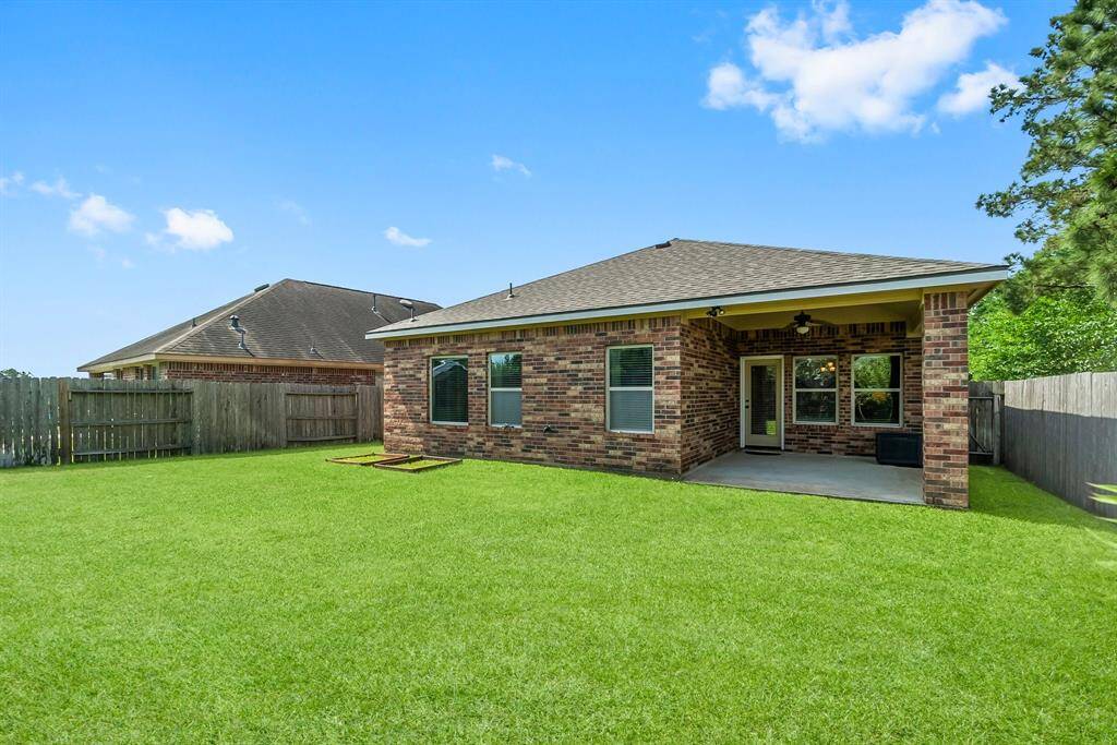 This photo showcases a brick home with a spacious, well-maintained backyard. It features a covered patio, perfect for outdoor relaxation, surrounded by a wooden privacy fence.