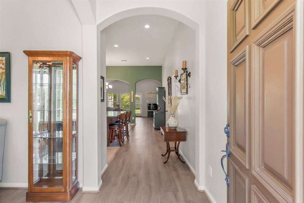 Welcome home! The entryway of this home has an arched doorway leading into an open-plan space. The view extends to a living area with large windows, offering natural light and a glimpse of greenery outside.