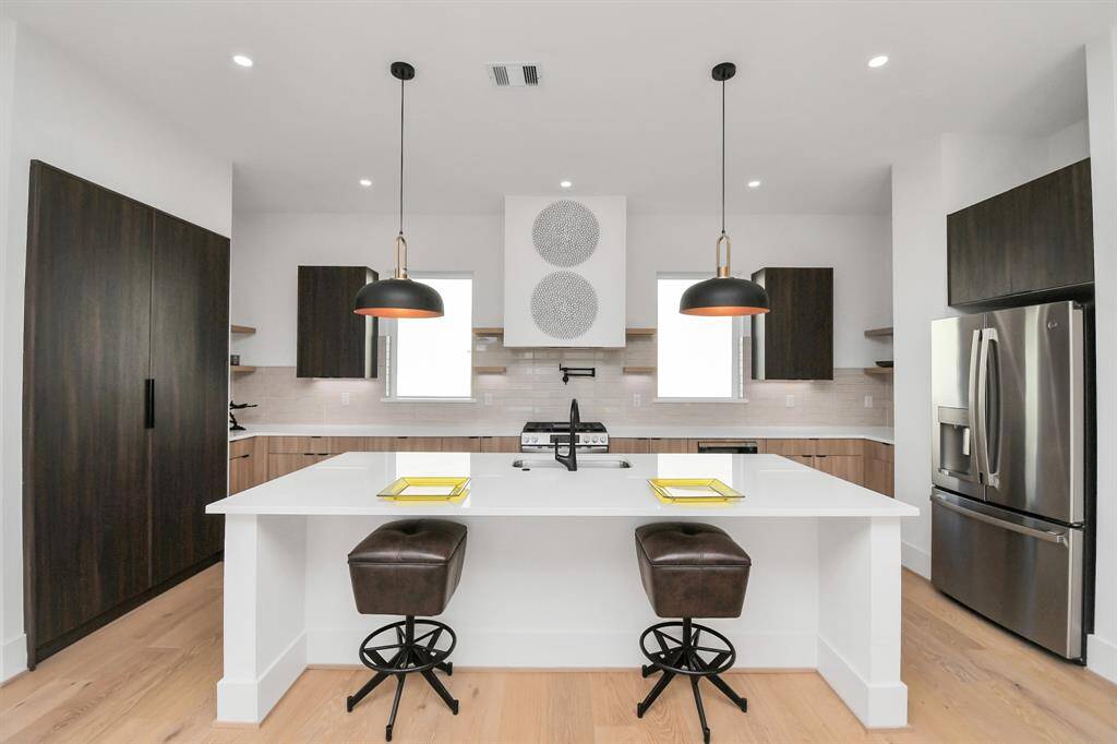 The spacious white quartz island offers ample counter space for meal prep and doubles as a gathering spot for family and guests.
