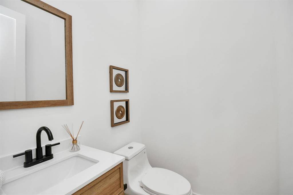 A conveniently located powder room with a solid wood vanity, designer faucet, and a square pedestal sink, perfect for guests.