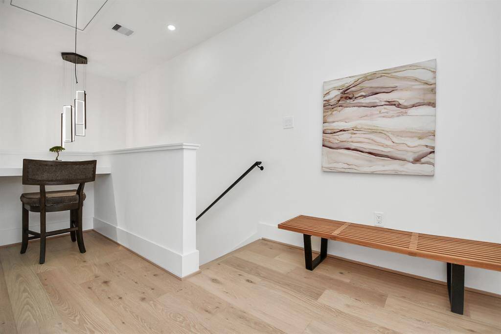 The third-floor landing features wide-plank wood flooring, a built-in desk area with elegant pendant lighting.