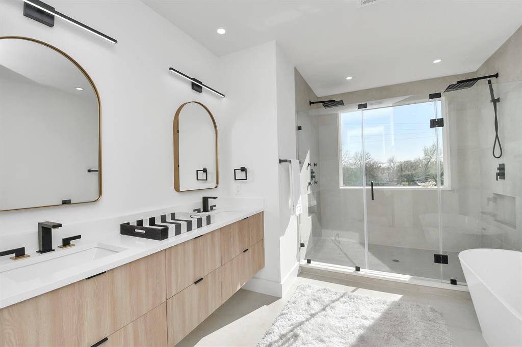 Primary Bathroom offers a stylish floating vanity with wood soft-close cabinets, quartz countertops, and white square undermount sinks, providing ample space for two.
