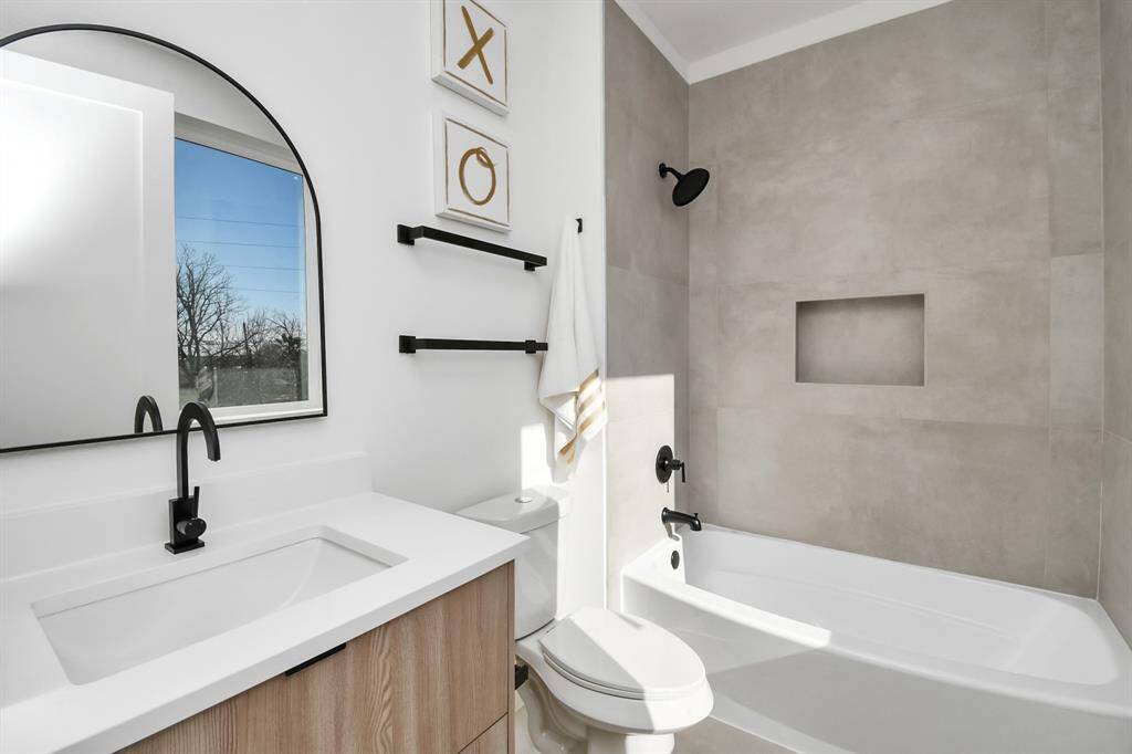 Third full bathroom on the third floor offers a tub and shower combo highlighted by large-format tile, a built-in niche for convenience, and a matte black rain showerhead.