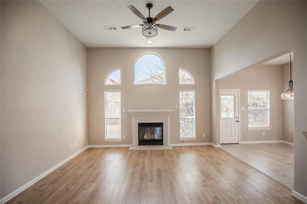 Large living room has high ceilings, log fire place and lots of natural lighting.