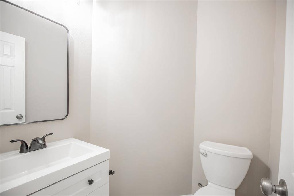 Updated half bathroom with new cabinet, lighting, mirror and toilet.