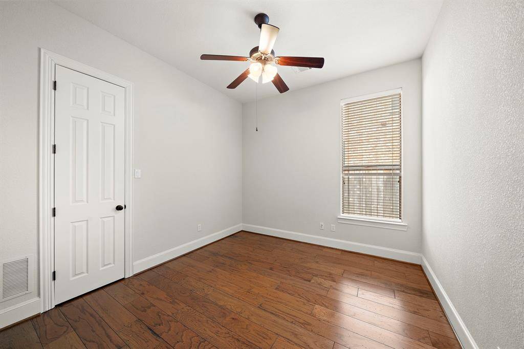 This room features hardwood floors, a ceiling fan with lights, and a window with blinds, offering a cozy and functional space.