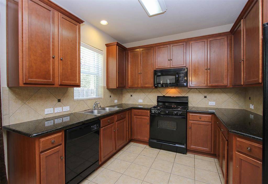 Kitchen with black granite counter-tops and black appliances