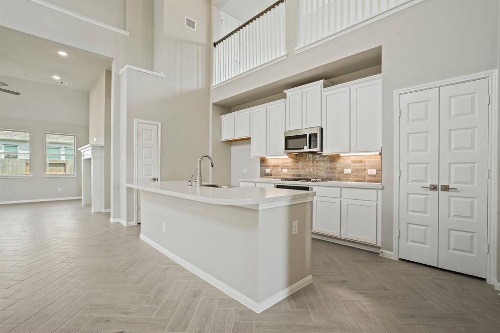 Island kitchen with white cabinets and quartz countertops
