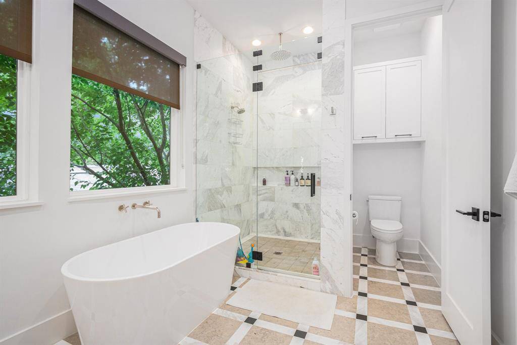 Luxurious primary bathroom featuring a soaking tub, separate shower, and spa-like finishes with custom design details throughout