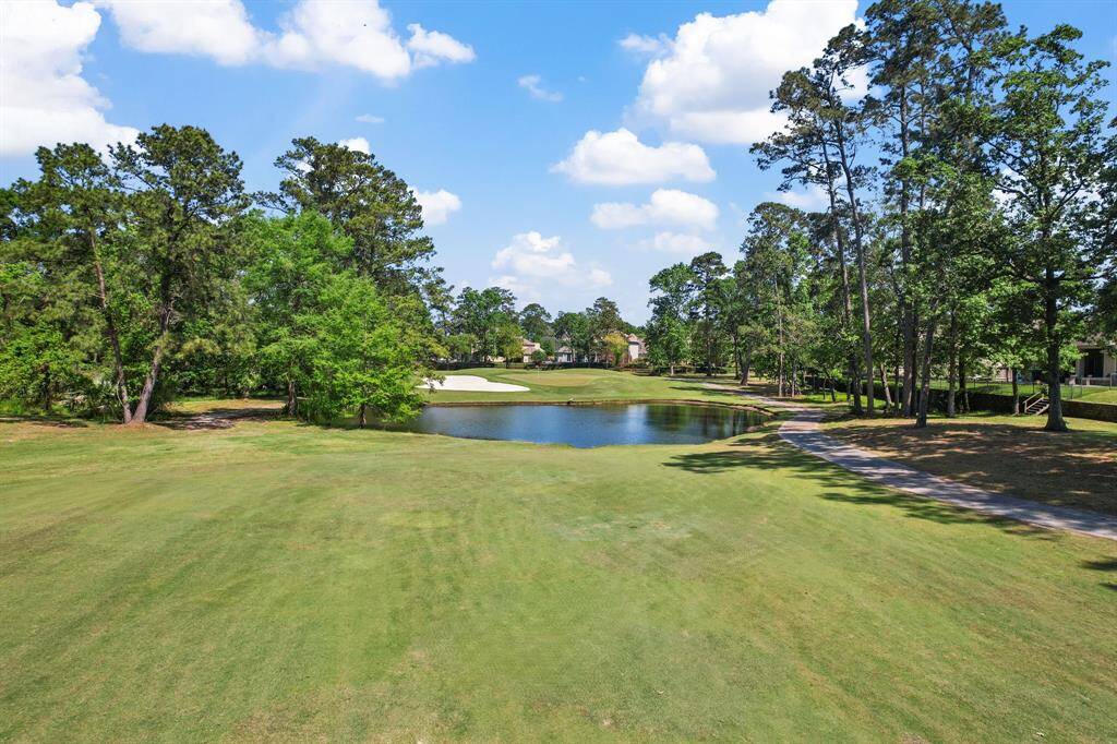 A beautiful serene golf course view with lush greenery, tall trees, and a small pond, offering a peaceful and picturesque setting for a homebuyer seeking a tranquil environment.