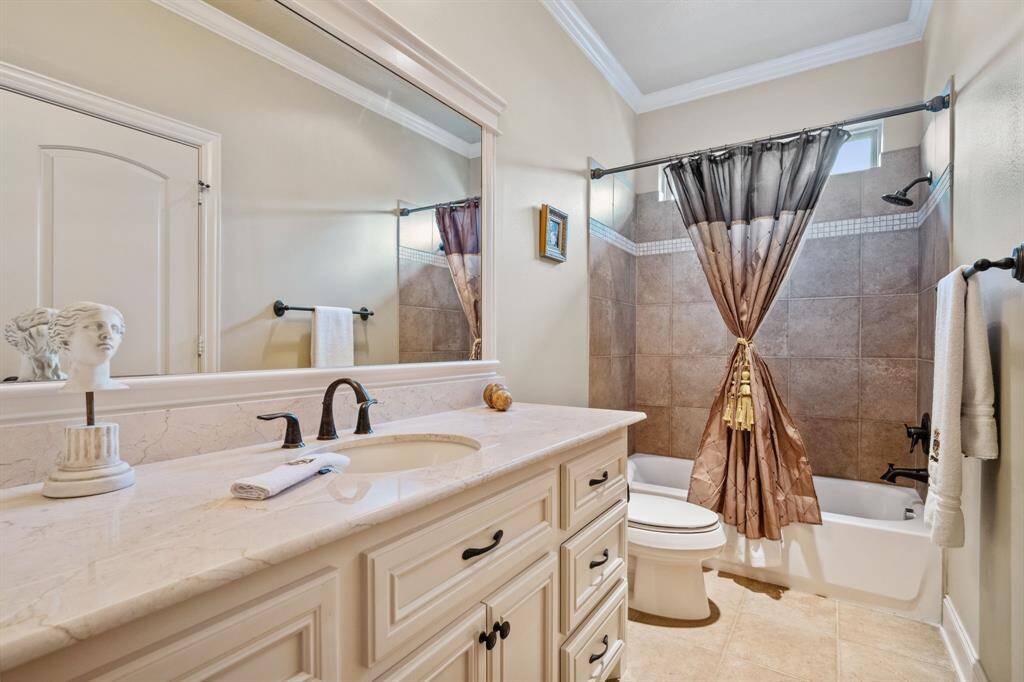 This bathroom features a clean, elegant design with a large vanity and marble countertop. The space is accented with neutral tones and stylish fixtures, creating a welcoming atmosphere.