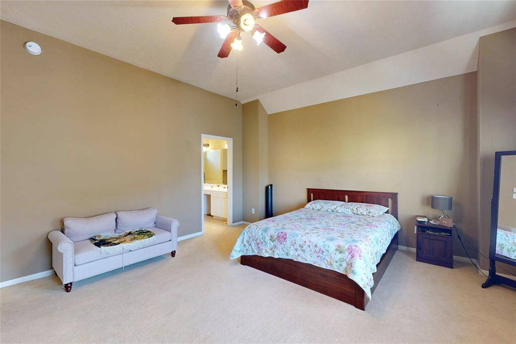 Another view of the primary bedroom. There's an ensuite bathroom visible through an open doorway, adding convenience and privacy.