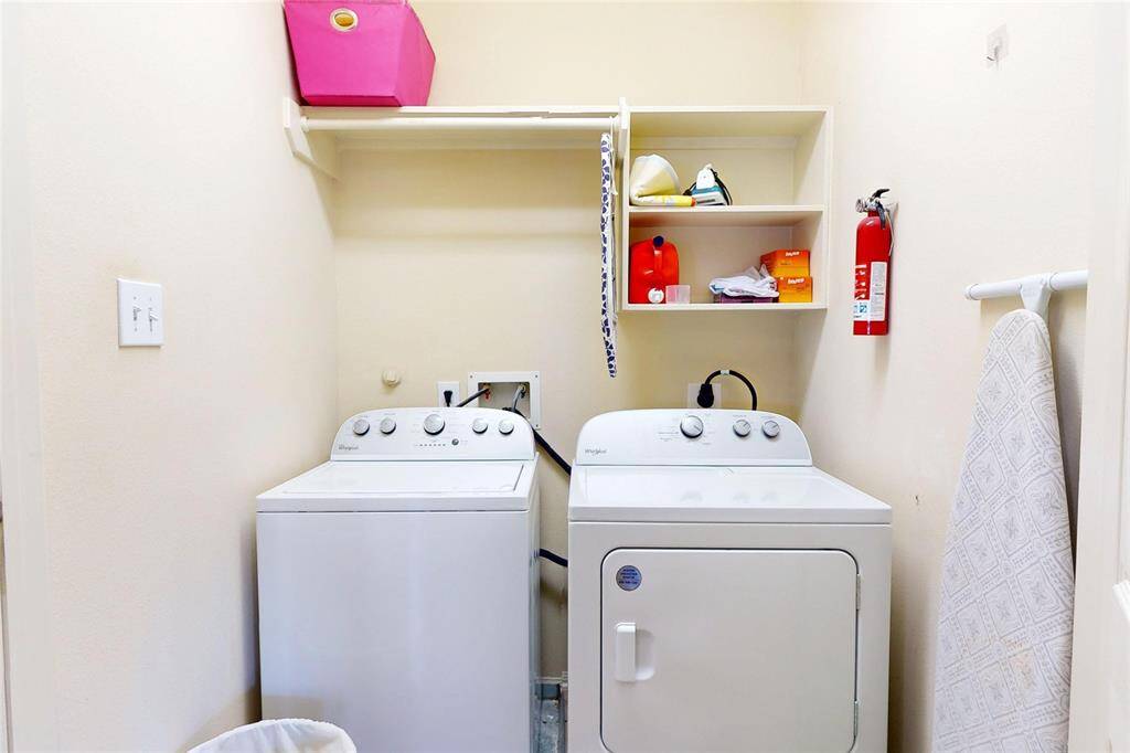 The inhouse (third floor) laundry room with full-size washer and dryer set. It includes shelving for storage and an ironing board, offering functionality and convenience.