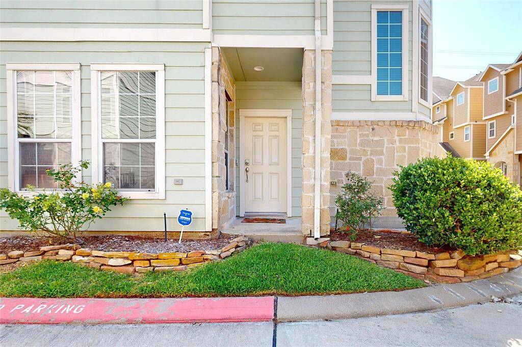 This photo shows the charming entrance of a townhouse with a light exterior and stone accents.