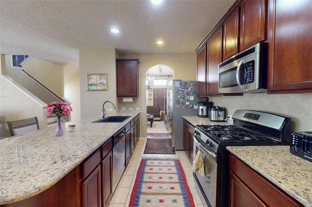 This kitchen features granite countertops, stainless steel appliances, and rich wood cabinetry. It has a spacious layout with a large island, and an open view to the adjacent dining room, perfect for entertaining.