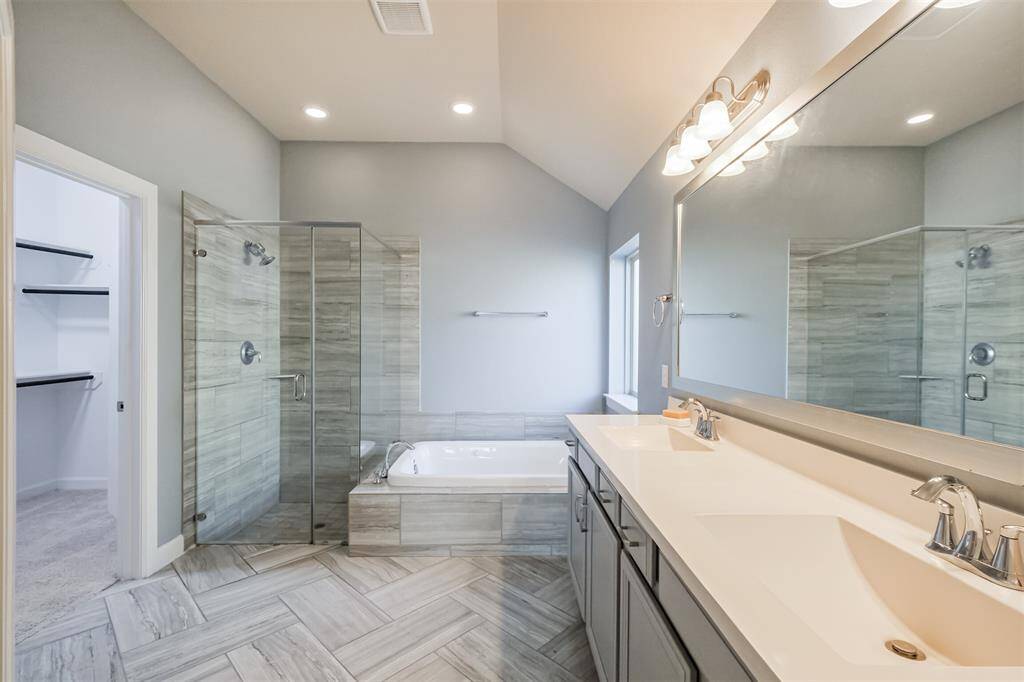 This bathroom features a modern design with a spacious walk-in glass shower, a separate jetted tub, and dual sinks with a large mirror. The neutral tones and ample lighting create a bright and inviting atmosphere.
