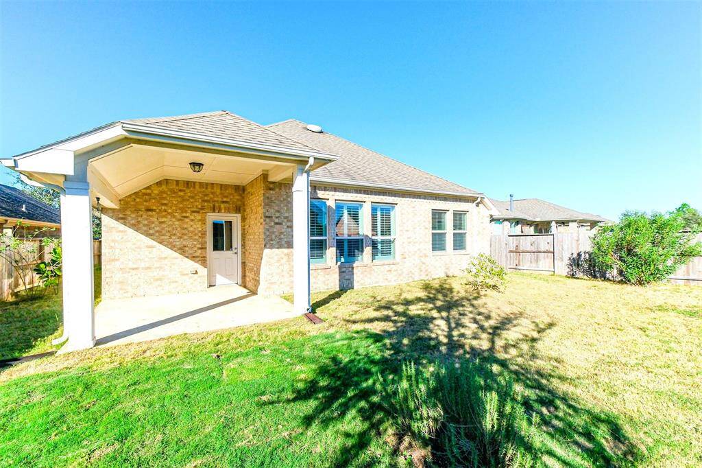 This back view of the home showcases your ample yard space and covered patio.