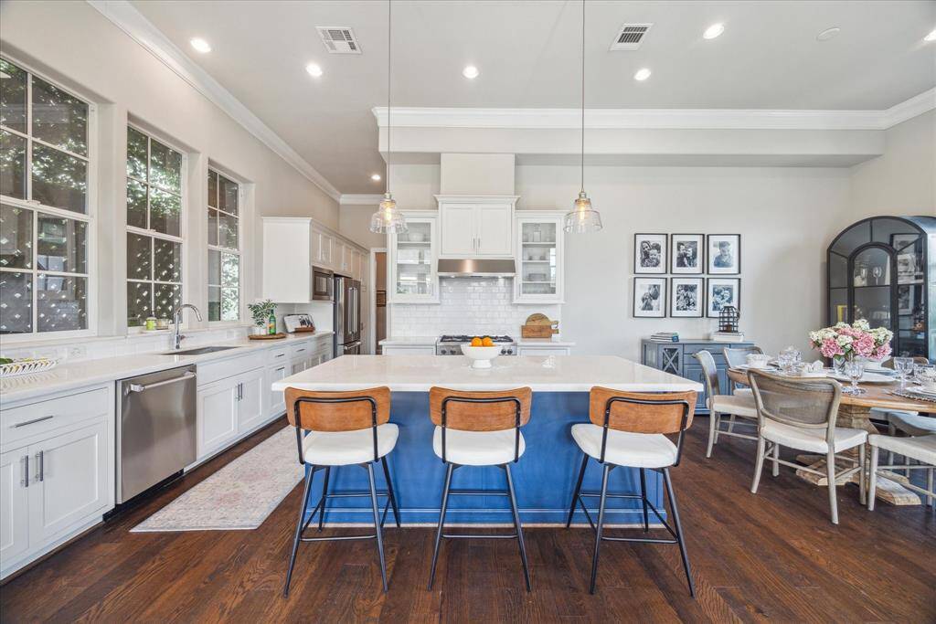 Kitchen features an oversized island accented in blue paint. Very little overhead cabinets keep the space open and airy.