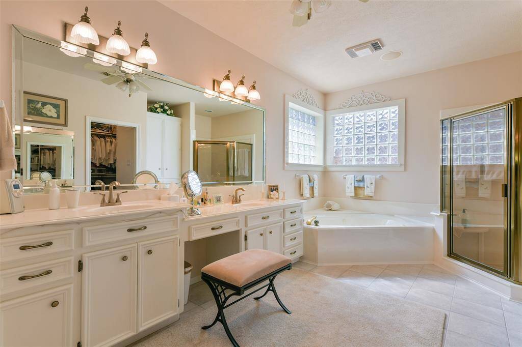 Primary bath with double sinks, vanity, large jetted soaking tub, and separate shower. Bathroom floor is tiled.