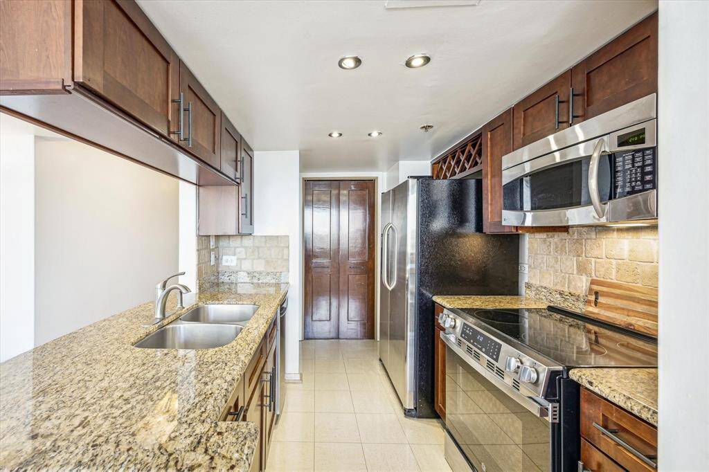 The kitchen features wood-stained Shaker cabinetry, granite countertops, and tiled backsplash. The utility room offers ample pantry storage, and included a washer and dryer.