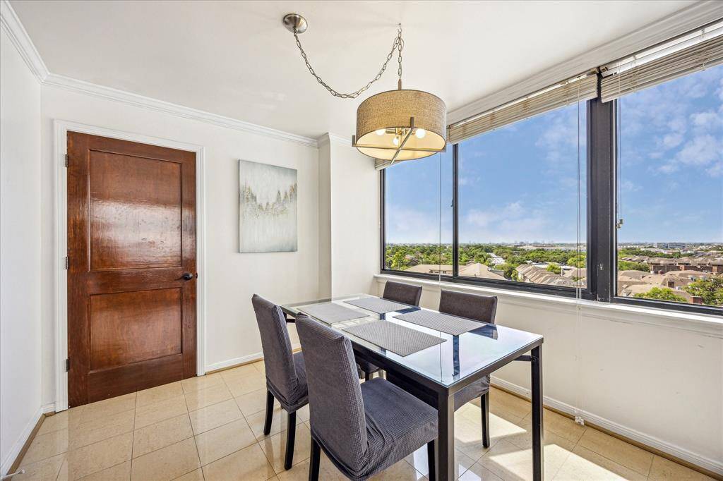 Elegant dining area with crown moulding, tile floors, chandelier lighting, and large windows with blinds for added light and style.