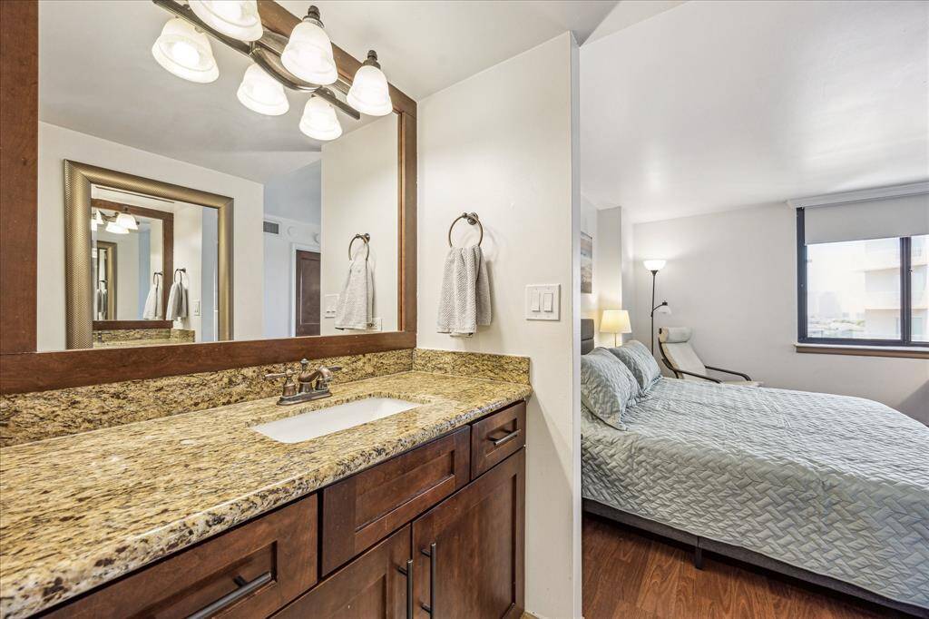 Primary bathroom has granite countertops, wall mounted framed mirror and lighting above.
