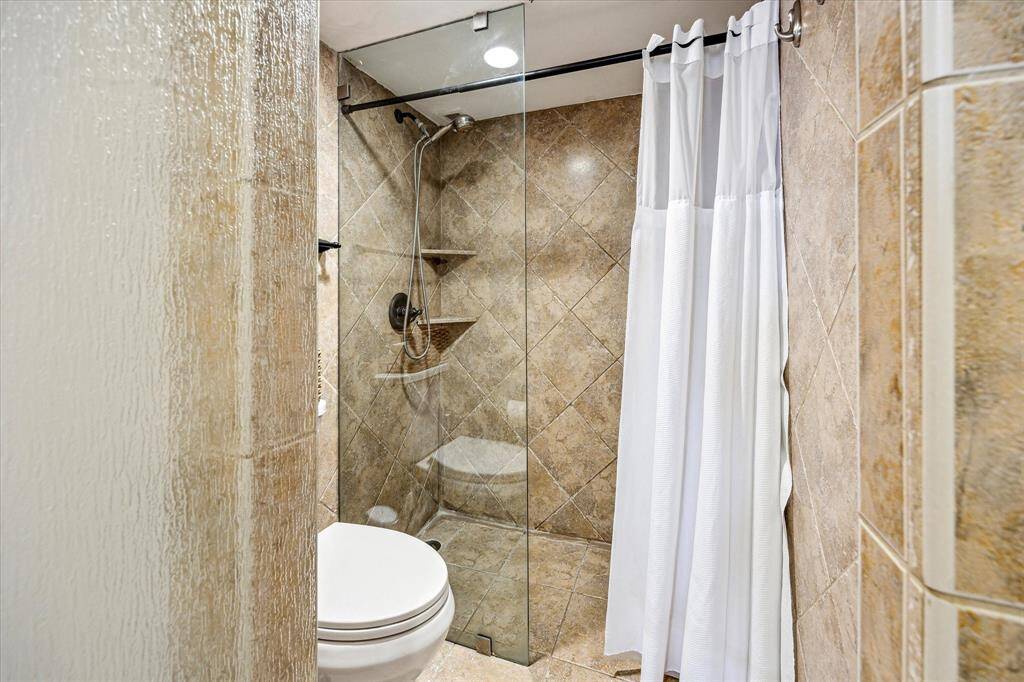 Primary bathroom features a frameless glass door that leads into the walk-in shower.